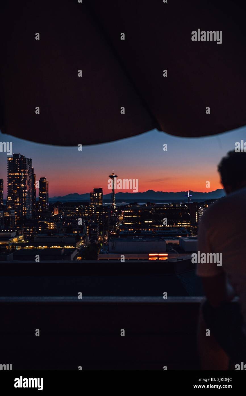 Uomo che guarda fuori al tramonto con lo skyline di Seattle dal ponte sul tetto di Capitol Hill Foto Stock