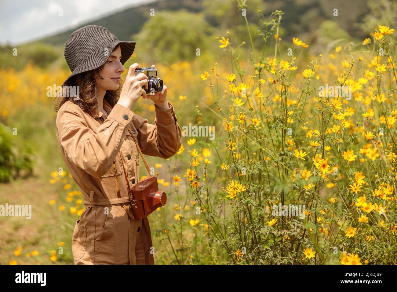 Sorridente turista femmina che fa foto di bellissimi fiori in Africa Foto Stock