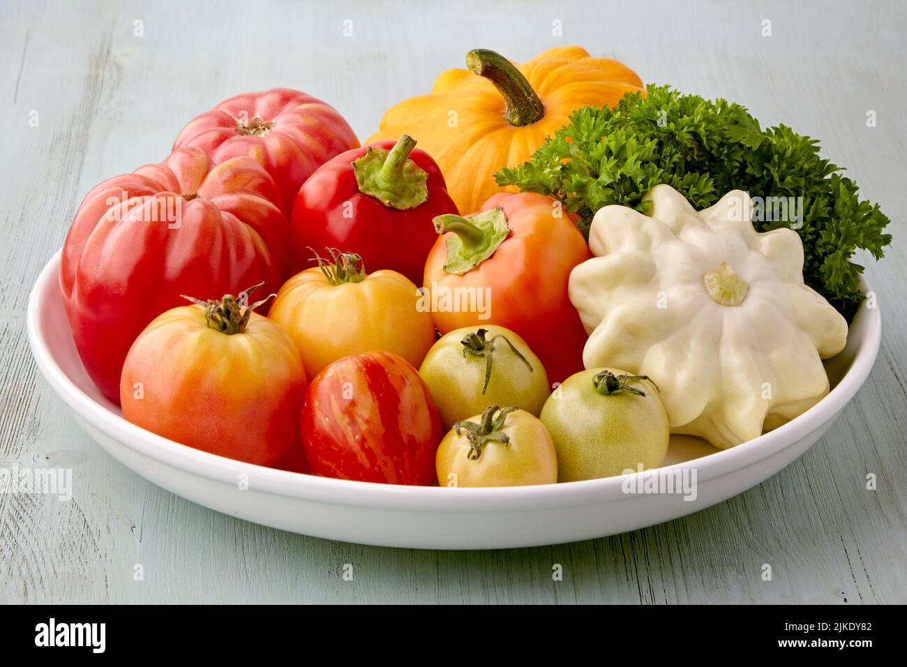 Piatto bianco con verdure biologiche fresche mature su un tavolo di legno blu Foto Stock
