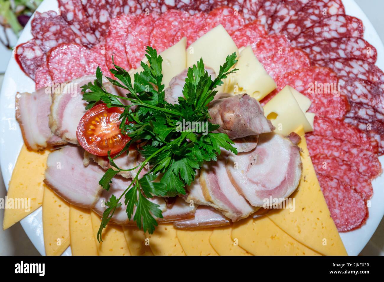 Un piatto di antipasti freddi con varie salsicce, carne e formaggio. Verdi e pomodori Foto Stock