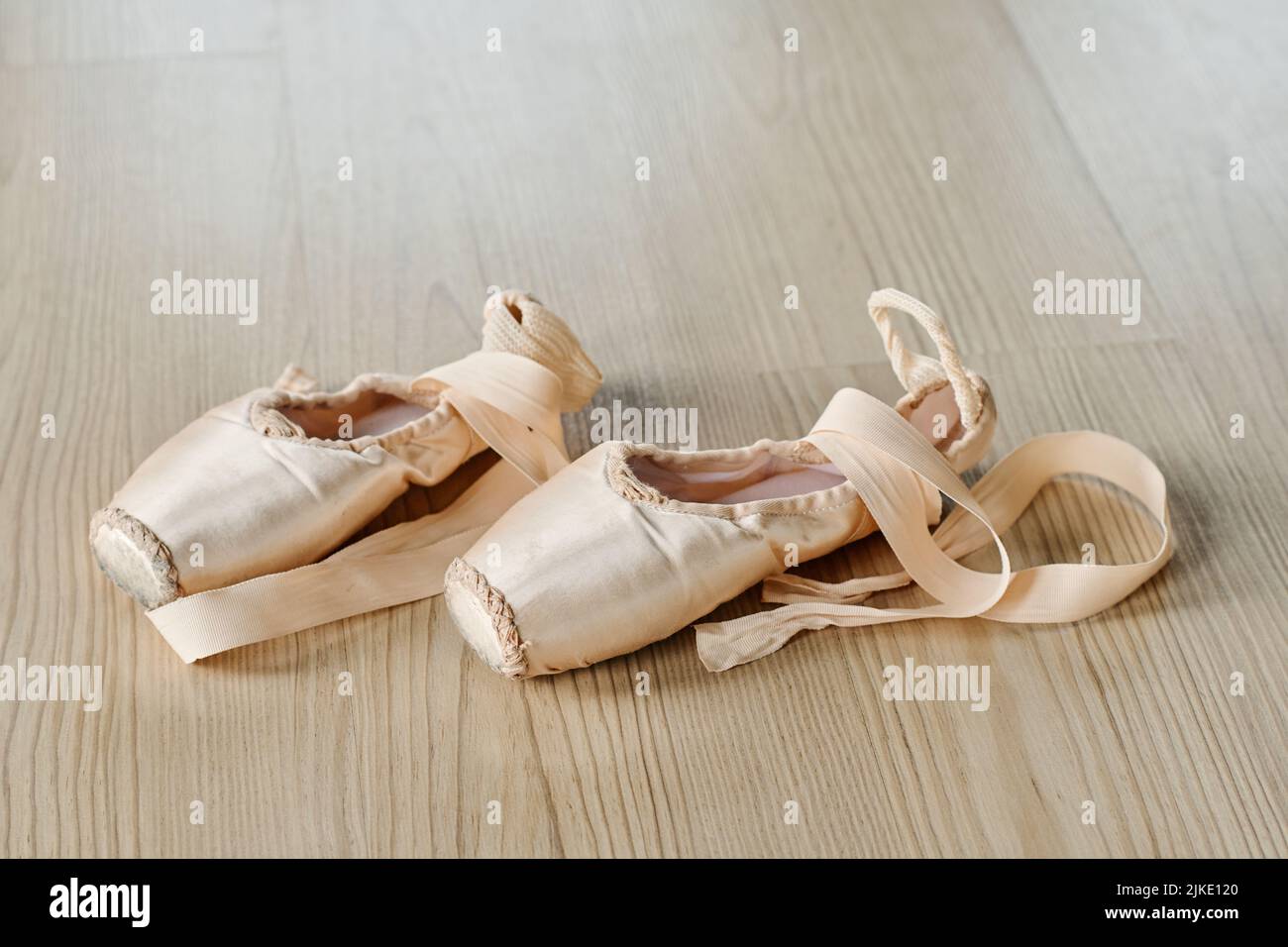 Coppia di nuove scarpe a punta unted di colore beige con nastri di seta sul pavimento della sala da ballo o della classe per le ripetizioni di esercizi di balletto Foto Stock