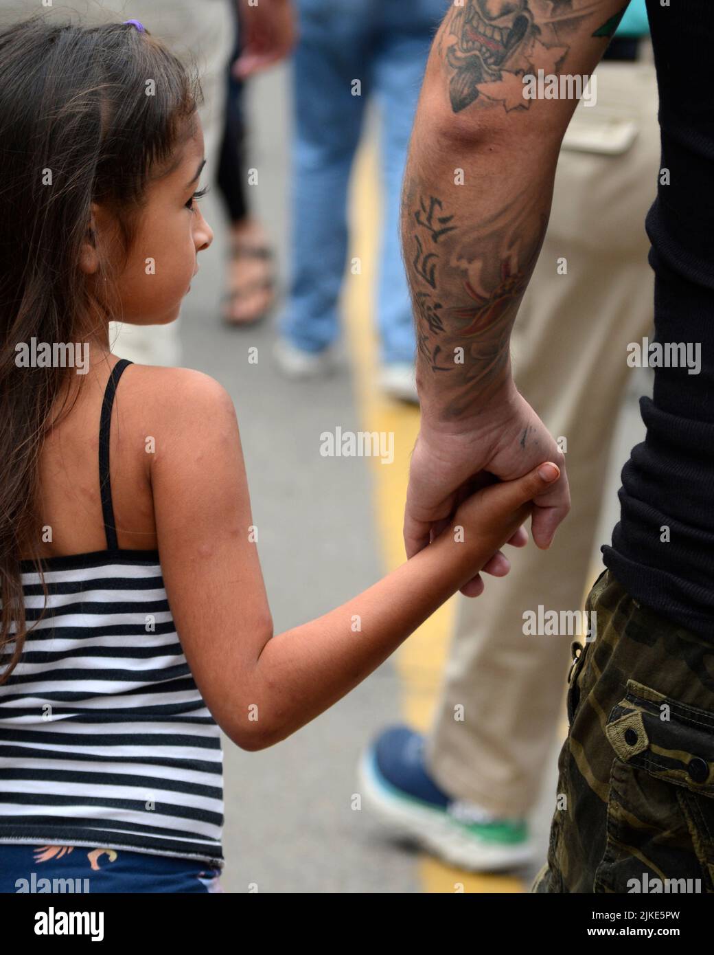 Un uomo e la sua giovane figlia tengono le mani mentre visitano un festival all'aperto a Santa Fe, New Mexico. Foto Stock
