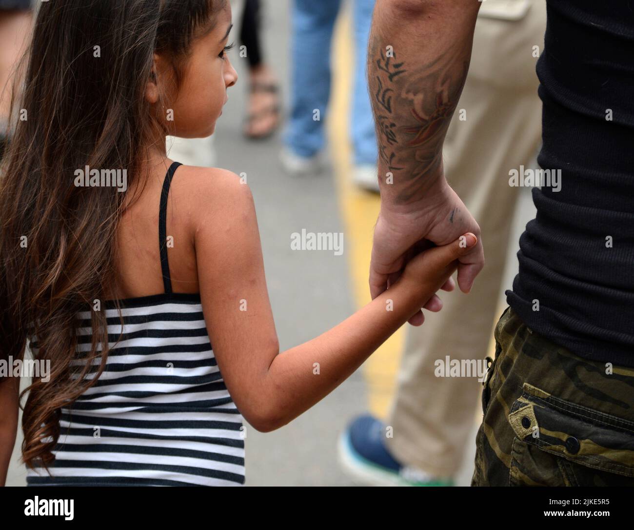 Un uomo e la sua giovane figlia tengono le mani mentre visitano un festival all'aperto a Santa Fe, New Mexico. Foto Stock