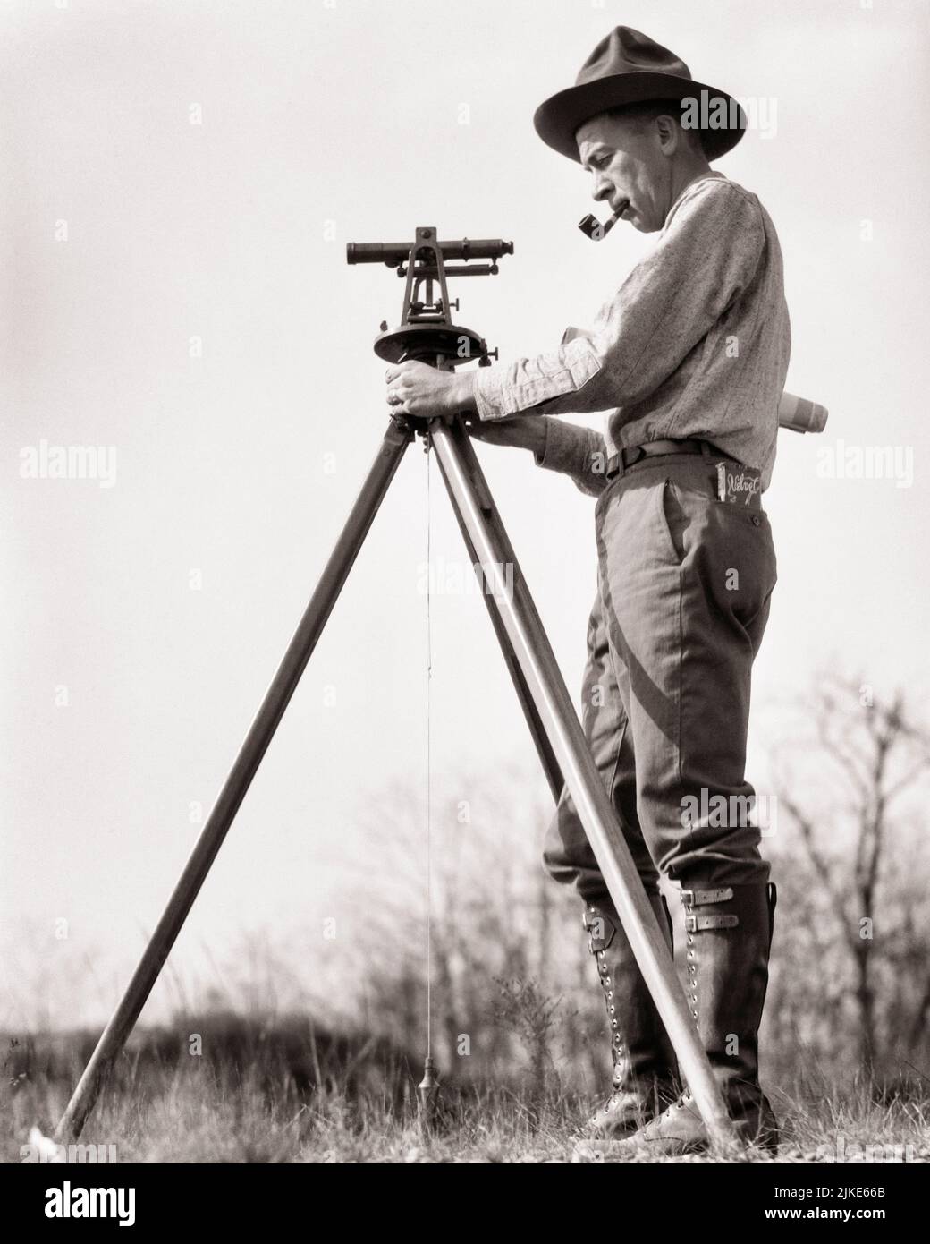 1920S 1930S UOMO UN SURVEYOR INDOSSARE UNA CAMPAGNA CAPPELLO FUMARE UN TUBO ISPEZIONARE UN CANTIERE CON UN LIVELLO DI TRANSITO SU UN TREPPIEDE - I40 HAR001 HARS FULL-LENGTH PERSONE MASCHI PROFESSIONE FIDUCIA DIRIGENTI TREPPIEDE B&W ABILITÀ OCCUPAZIONE OTTICA ABILITÀ AVVENTURA CAREERS LAVORO A BASSO ANGOLO A OCCUPAZIONE PROFESSIONI SURVEYOR BOSS CAMPAGNA CONCETTUALE ISPEZIONE DI CLASSE INDAGINE INFRASTRUTTURA INDAGINE DIPENDENTI MANAGER LIVELLO MEDIO-ADULTO MEDIO-ADULTO MAN PROJECT TRANSIT BIANCO E NERO HAR001 CHE LAVORA IN VECCHIO STILE Foto Stock
