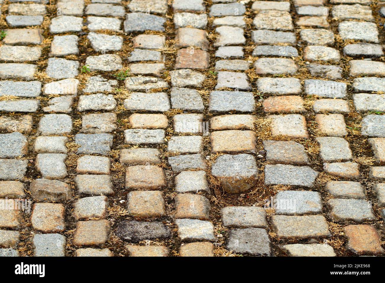 pietre di pavimentazione di pietre rettangolari e quadrate di diversi colori e dimensioni. Manca una pietra dalla strada acciottolata. Foto Stock