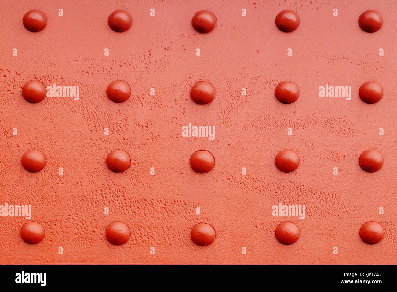 parete, superficie rossa con punti in rilievo che formano un modello simmetrico Foto Stock