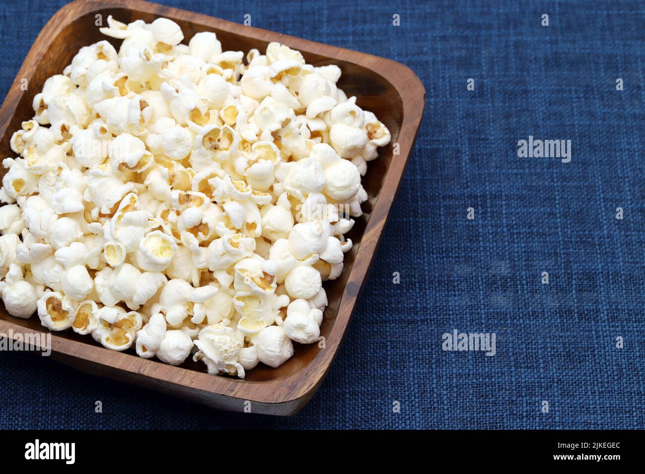 Popcorn in ciotola di legno sul tavolo, vista laterale, primo piano Foto Stock