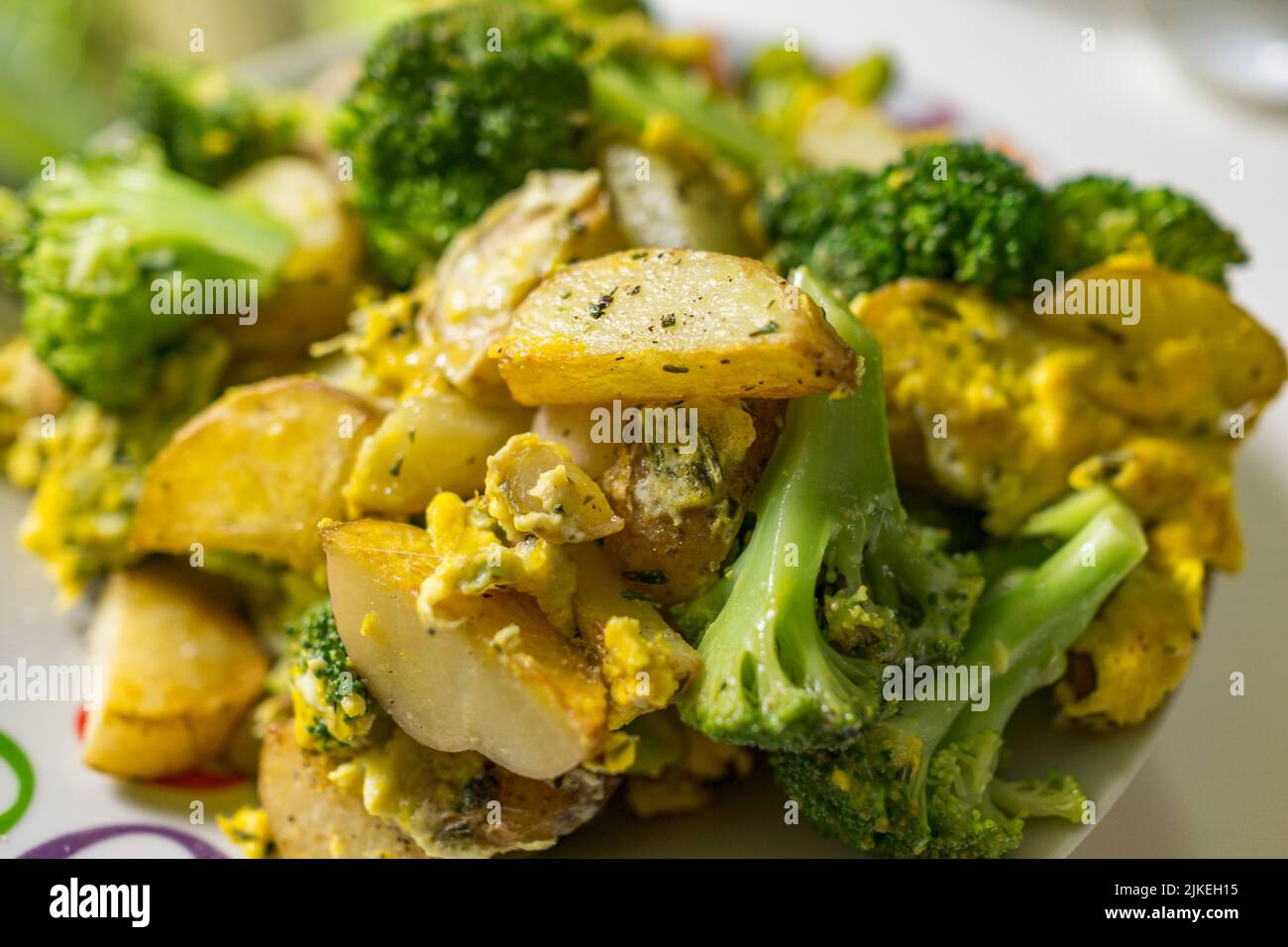 Broccoli, patate e uova strapazzate con rosmarino tritato e fiocchi di pepe hanno fatto un pasto in una pentola e una ciotola per servire. Foto Stock