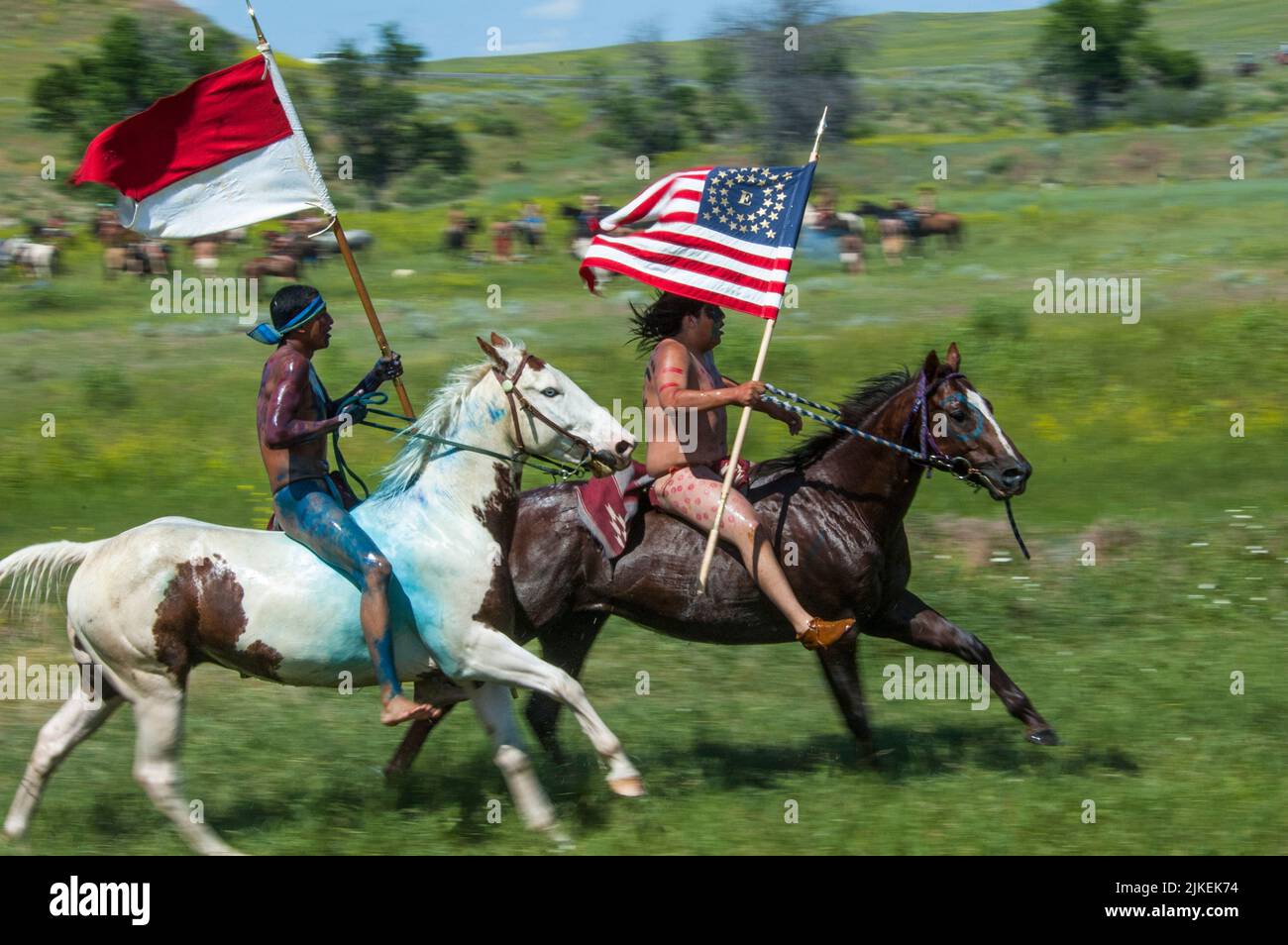 I guerrieri di Sioux corrono a cavallo con le bandiere degli Stati Uniti durante la rievocazione di Custers Last Stand sullo storico campo di battaglia del Little Bighorn National Monu Foto Stock