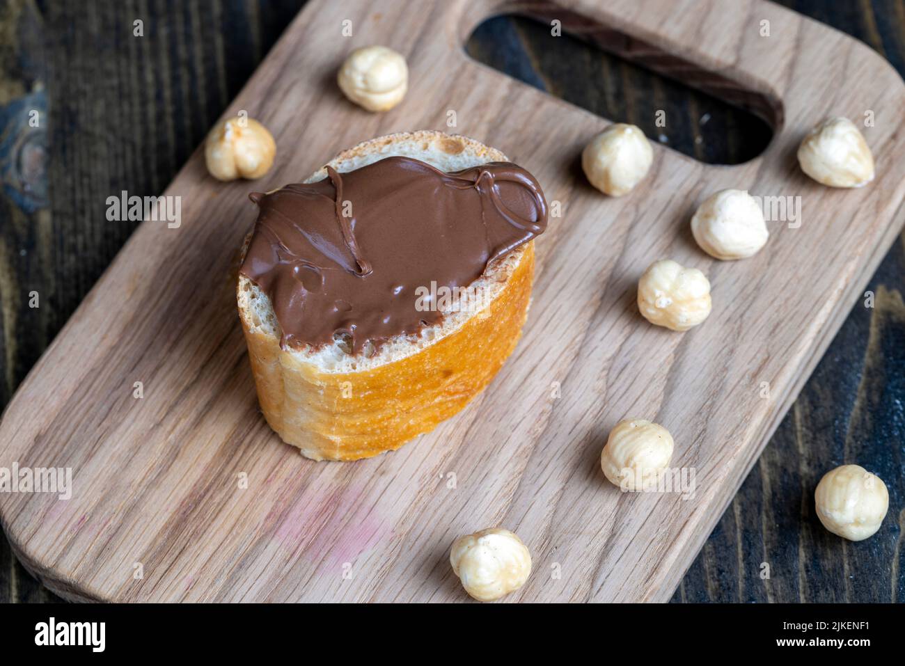 burro di cioccolato spalmato su una baguette, burro di cioccolato dolce spalmato su una baguette durante la preparazione di un semplice dessert a casa Foto Stock