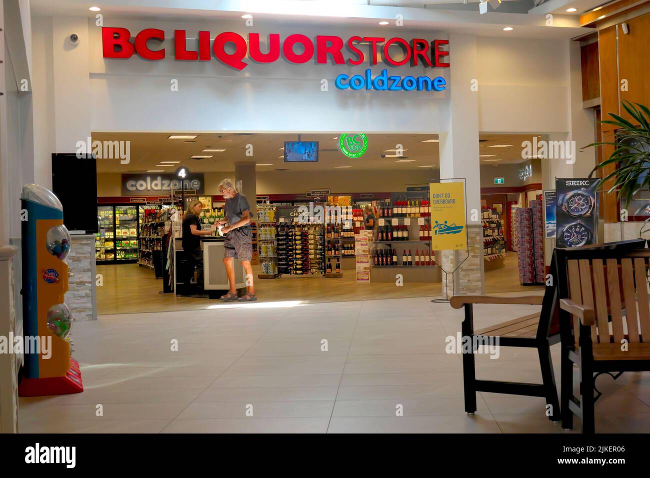 Un cliente di sesso maschile che acquista una bottiglia di liquore da un impiegato di sesso femminile in un negozio di liquori B. C. situato in un centro commerciale di Maple Ridge, B. C., Canada. Foto Stock