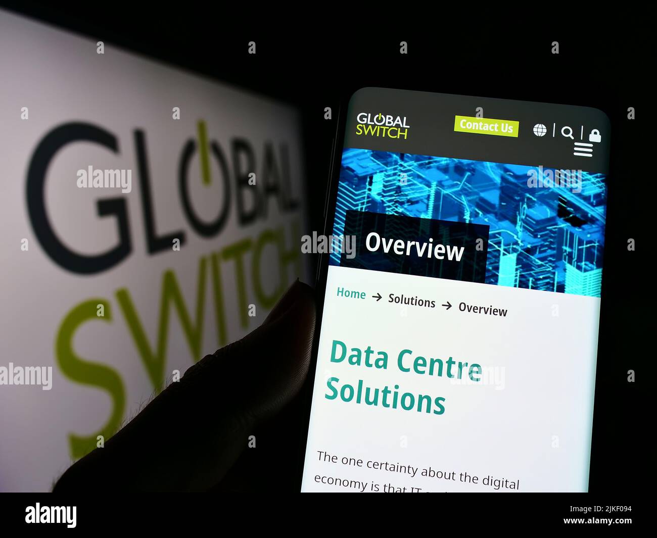 Persona che tiene uno smartphone con la pagina Web della società britannica di data center Global Switch Ltd. Sullo schermo con il logo. Concentrarsi sul centro del display del telefono. Foto Stock