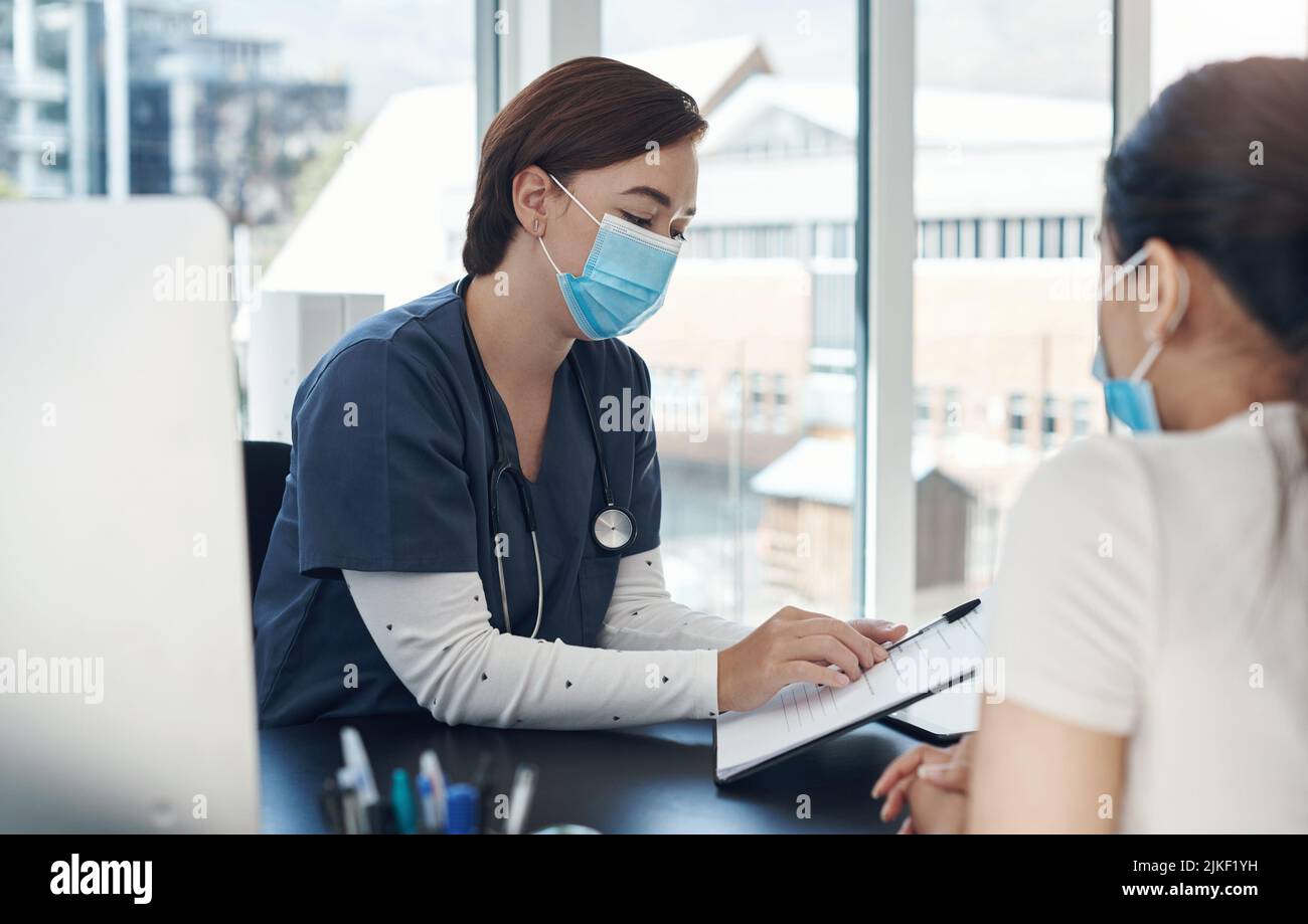 Youre andando avere bisogno di questi documenti quando ottenete dimessi. Un medico femminile giovane che scrive le informazioni di un paziente in un ufficio. Foto Stock
