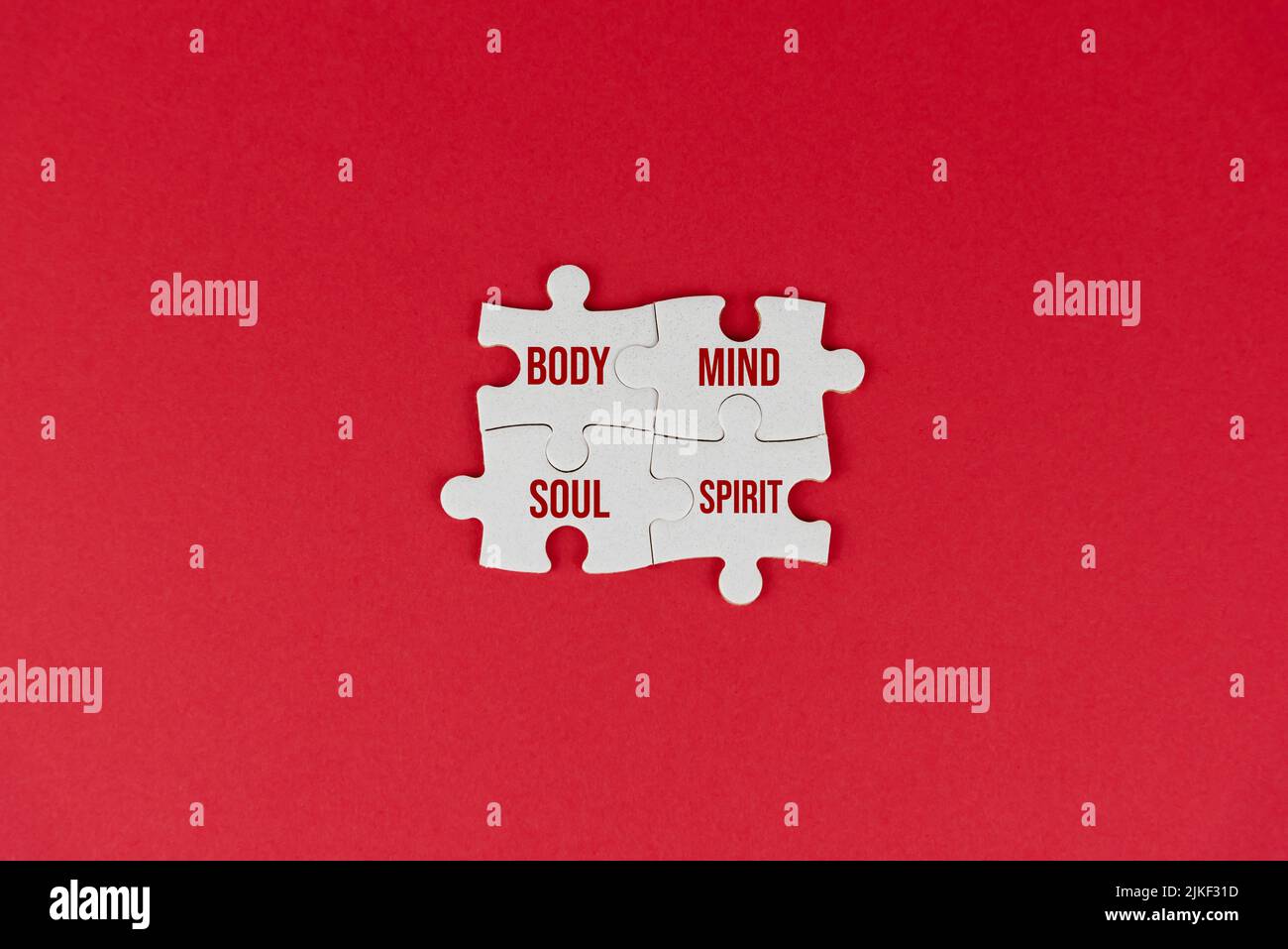 Corpo mente anima e spirito. Concetto di connessione di spiritualità con una sola parola su quattro puzzle su sfondo rosso. Parole spirituali per la salute mentale Foto Stock