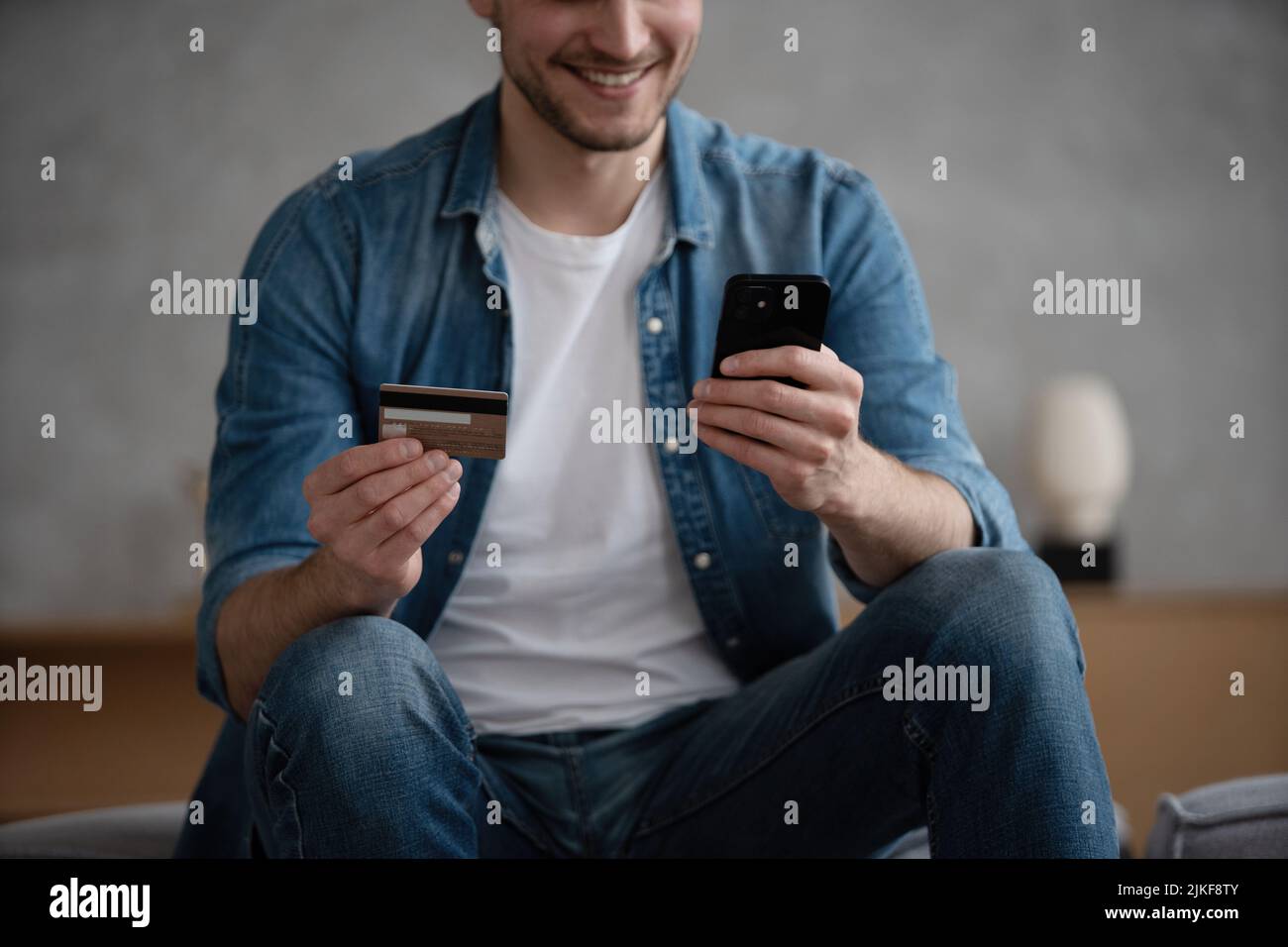 Primo piano di sorridente uomo caucasico tenere cellulare effettuare l'acquisto di pagamento online con carta di credito, felice maschio shopping online su smartphone, utilizzare in Foto Stock