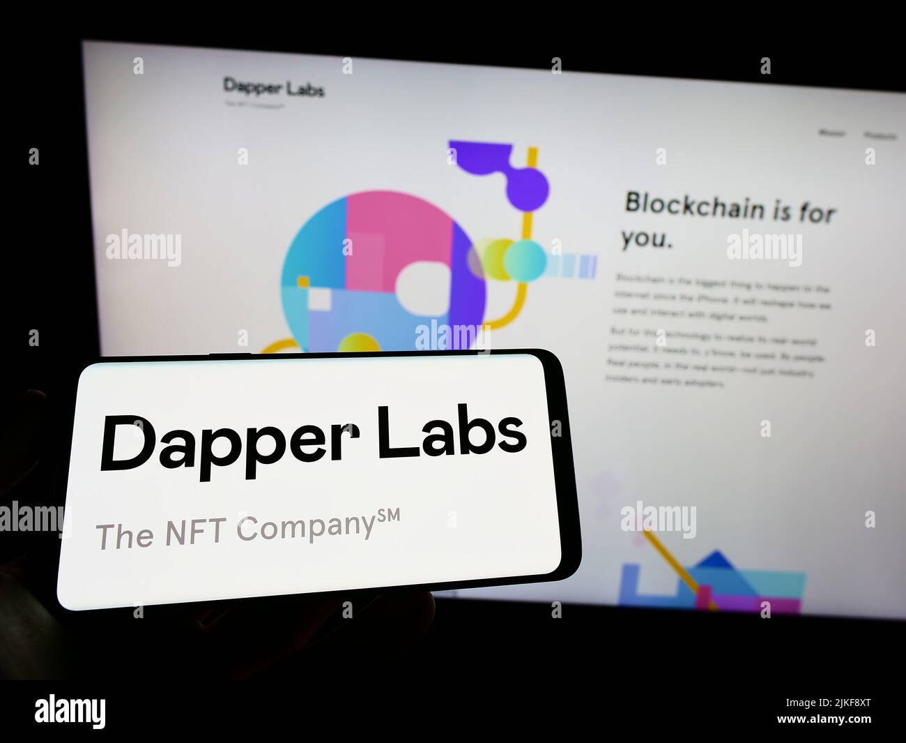 Persona che tiene il cellulare con il logo della società canadese di blockchain Dapper Labs Inc. Sullo schermo di fronte alla pagina web aziendale. Mettere a fuoco sul display del telefono. Foto Stock