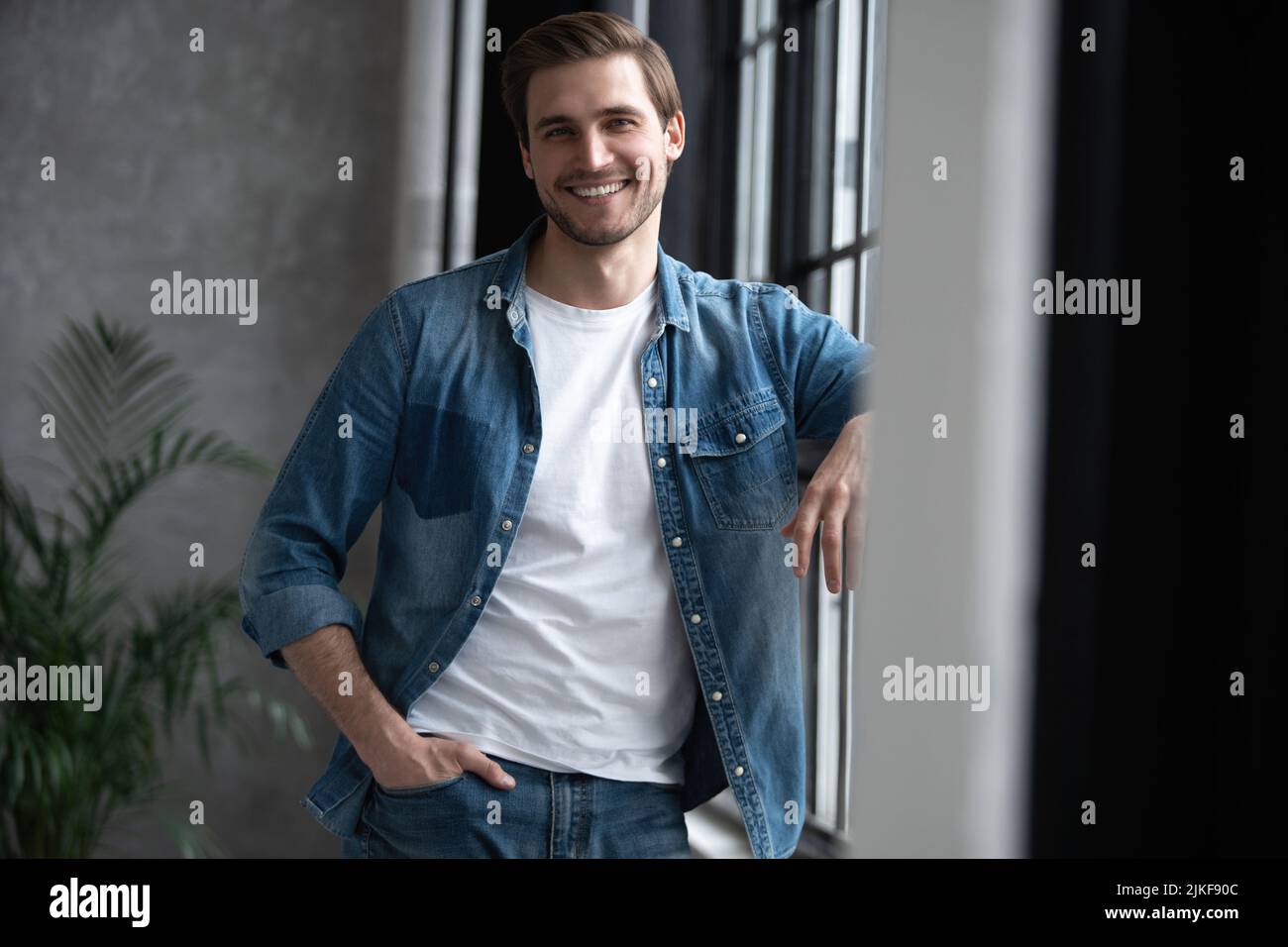 Immagine di un giovane uomo sorridente positivo in casa a casa guardando macchina fotografica. Foto Stock