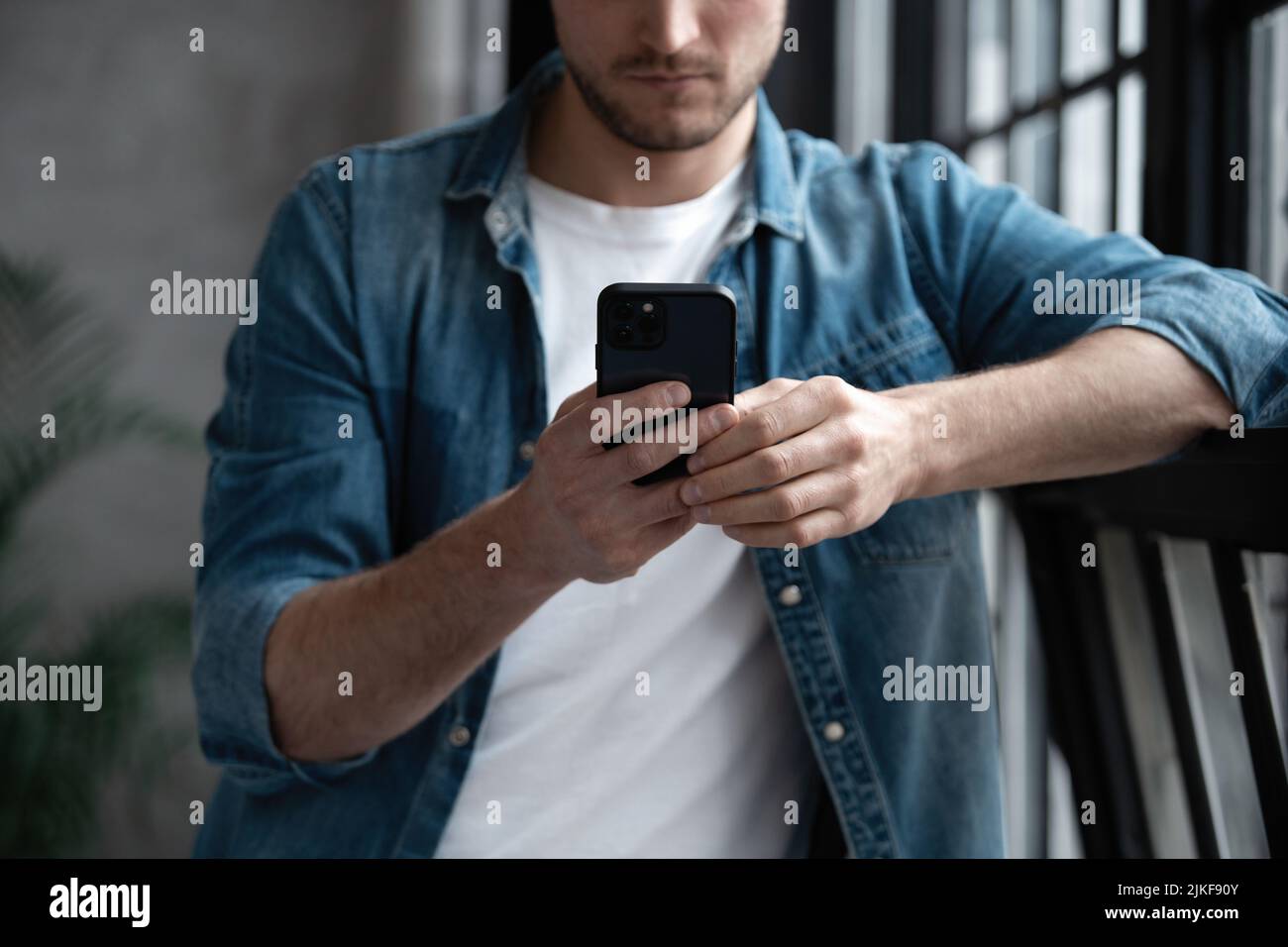 Ritratto di un giovane sorridente attraente che indossa abiti casual utilizzando il telefono cellulare Foto Stock