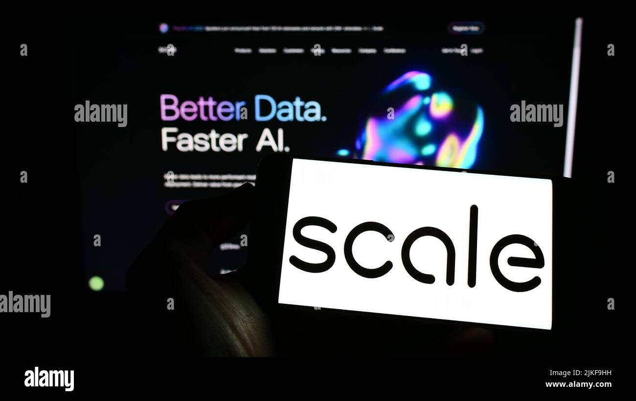 Persona che tiene il cellulare con il logo della società di software statunitense Scale ai Inc. Sullo schermo di fronte al sito web aziendale. Mettere a fuoco sul display del telefono. Foto Stock