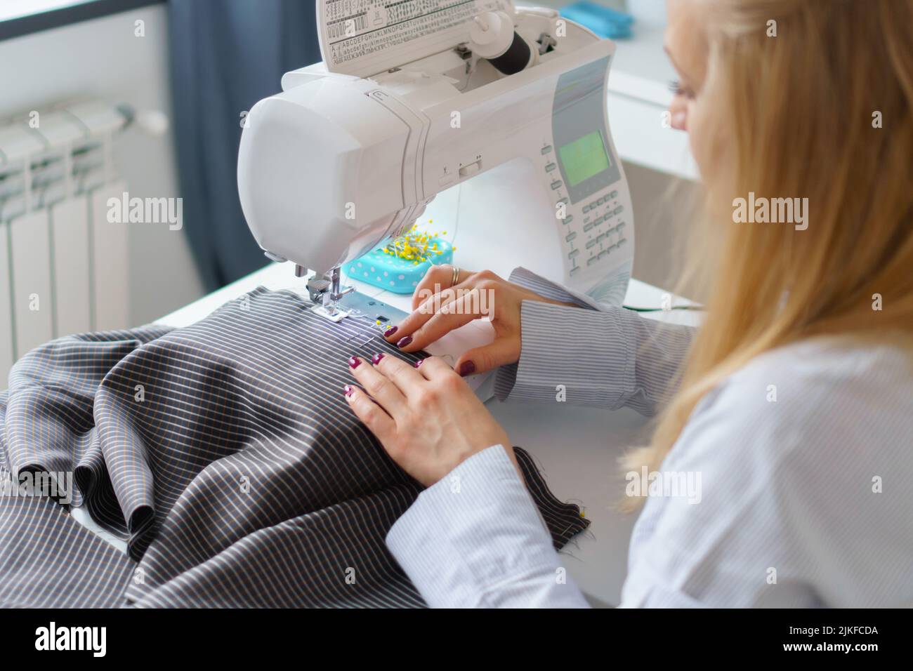 La donna di seamstress lavora sulla macchina da cucire. Le mani del dressaker lavorano alla fabbrica di cucire Foto Stock