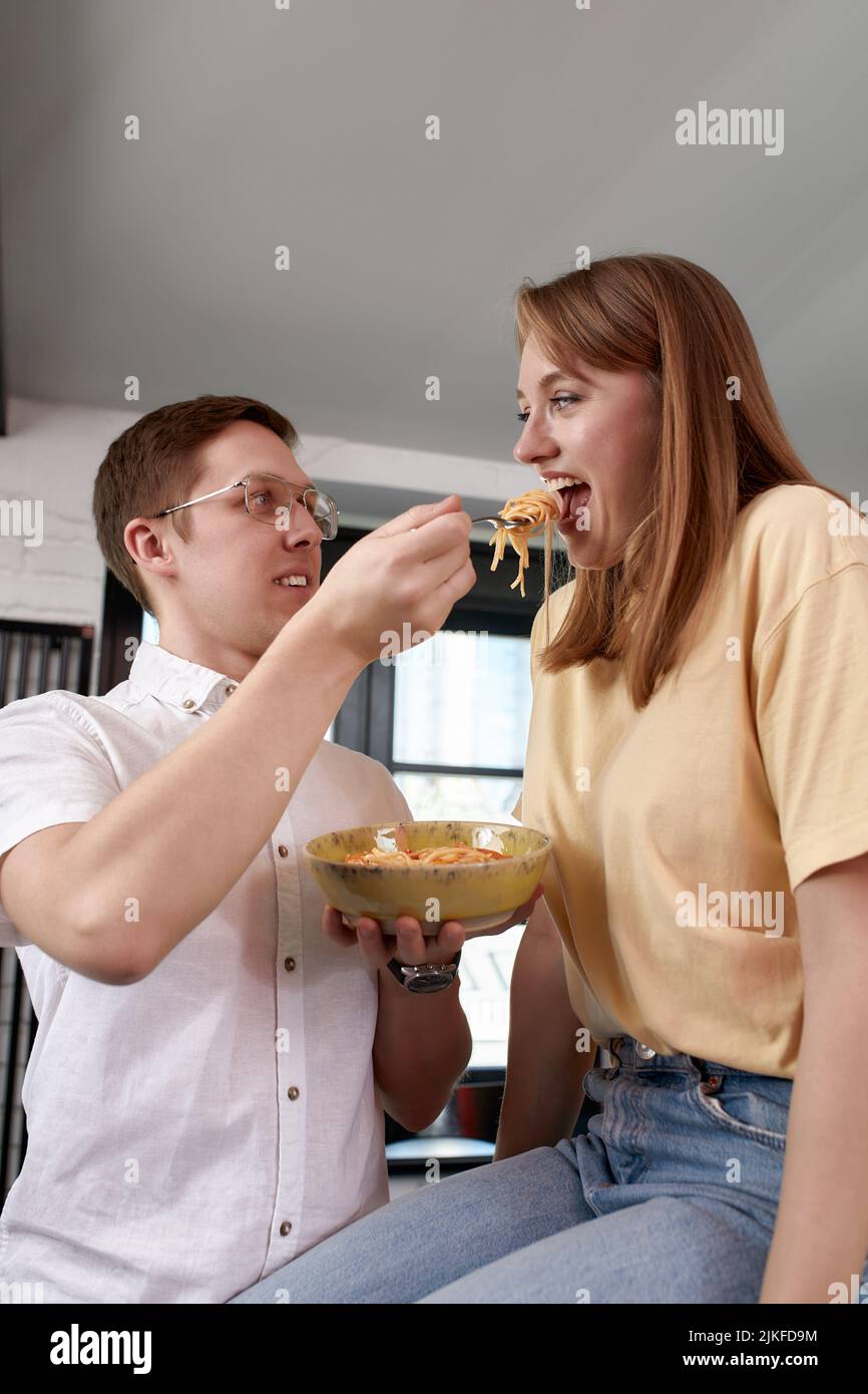 Sorridendo amorevole marito che alimenta moglie, giovane coppia che gode momento tenero, data romantica, divertirsi, mangiare cucina giapponese, felice famiglia spesa Foto Stock