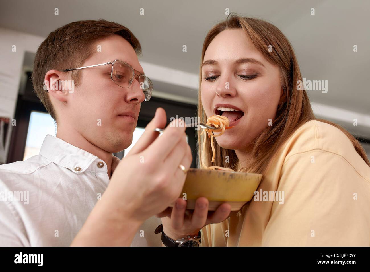 Sorridendo amorevole marito che alimenta moglie, giovane coppia che gode momento tenero, data romantica, divertirsi, mangiare cucina giapponese, felice famiglia spesa Foto Stock