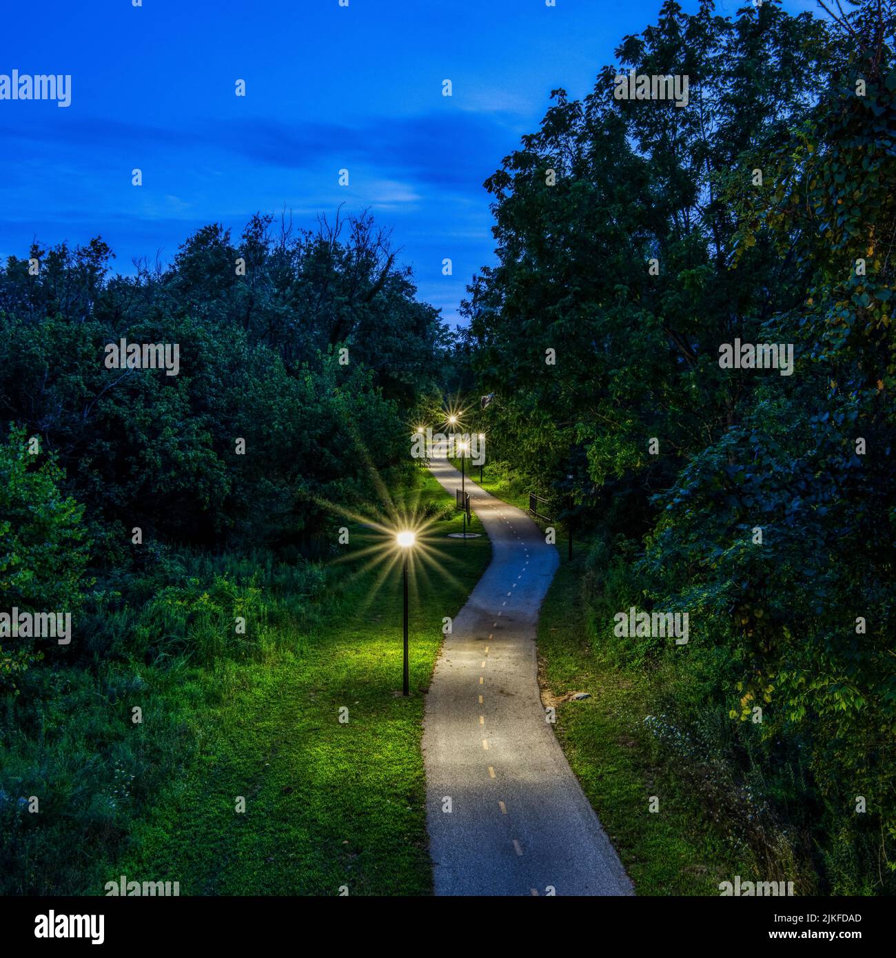 Un alto angolo di un percorso illuminato con lanterne in un parco verde al crepuscolo in Columbia, Maryland Foto Stock