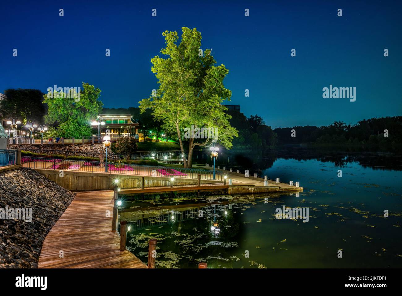Una vista panoramica di un portico di legno illuminato con lanterne contro un lago al crepuscolo in Colombia, Maryland Foto Stock