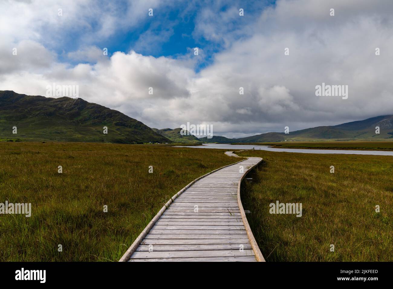 Una vista sul sentiero costiero della montagna di Claggan e sul lungomare con la catena montuosa del Nephir sullo sfondo Foto Stock