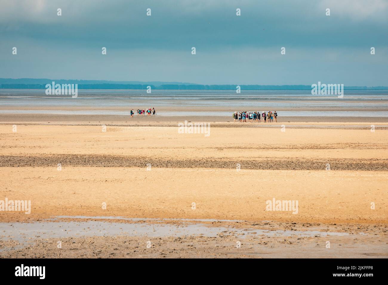 Gruppi di turisti che attraversano la Manica dalla Plage du Bec d'Andaine a piedi per raggiungere il Monte Saint-Michel Foto Stock