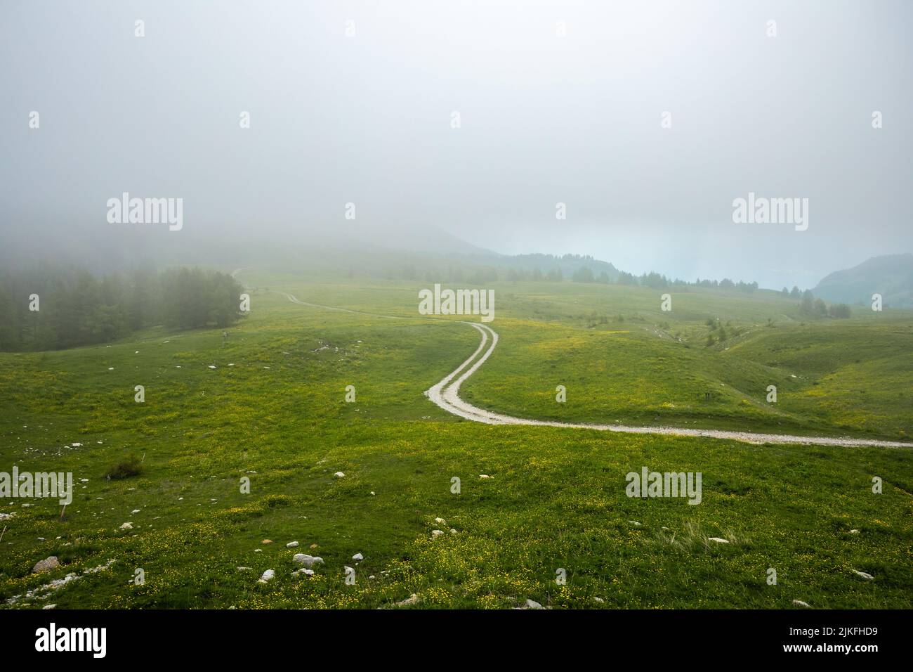 Col De la Cayolle. Strada sterrata che si snoda tra le montagne durante la nebbia delle Alpi francesi Foto Stock