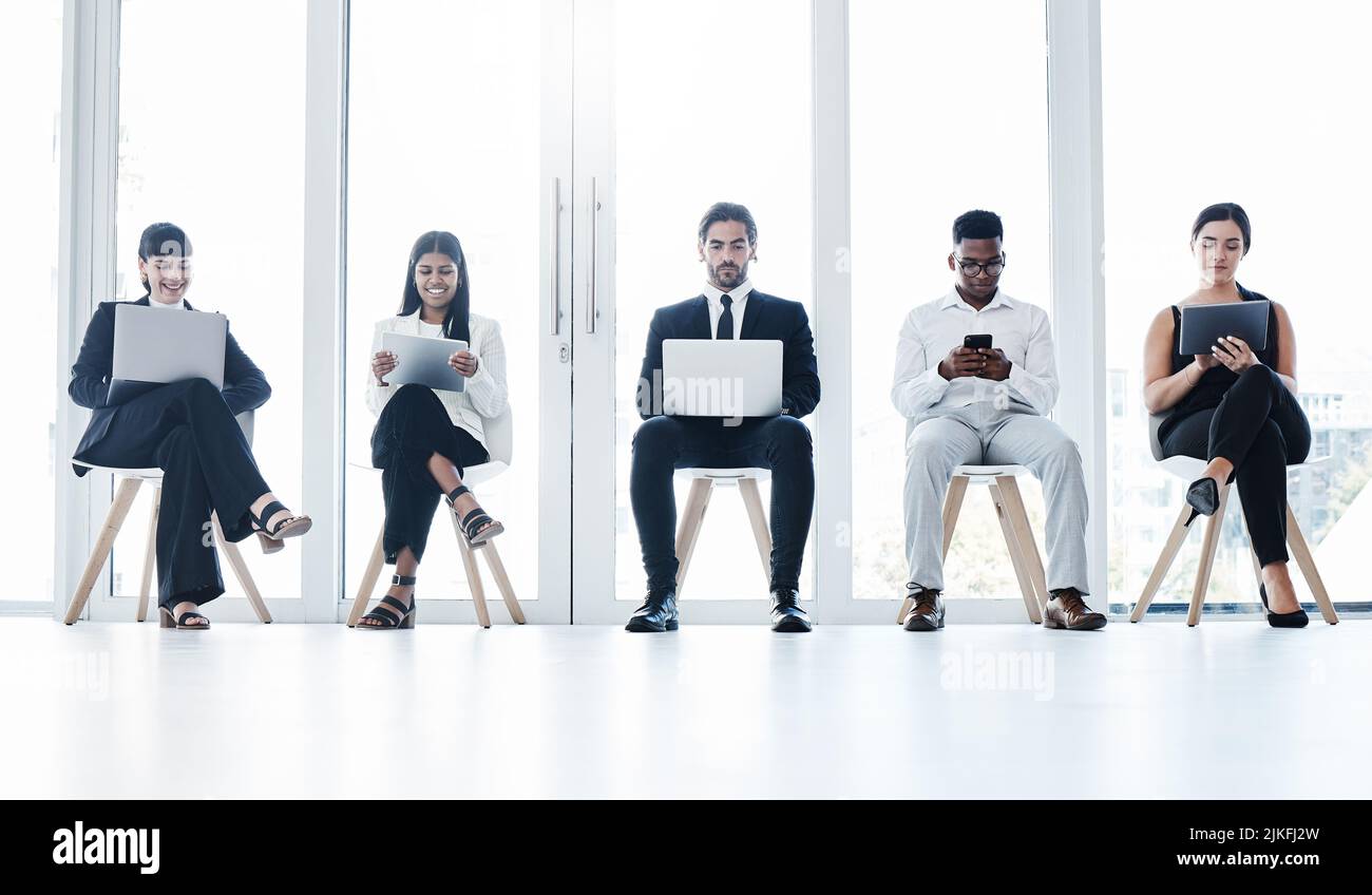 Riunirsi per tutte le attività aziendali. Un gruppo di aziende che utilizzano dispositivi digitali in ufficio. Foto Stock