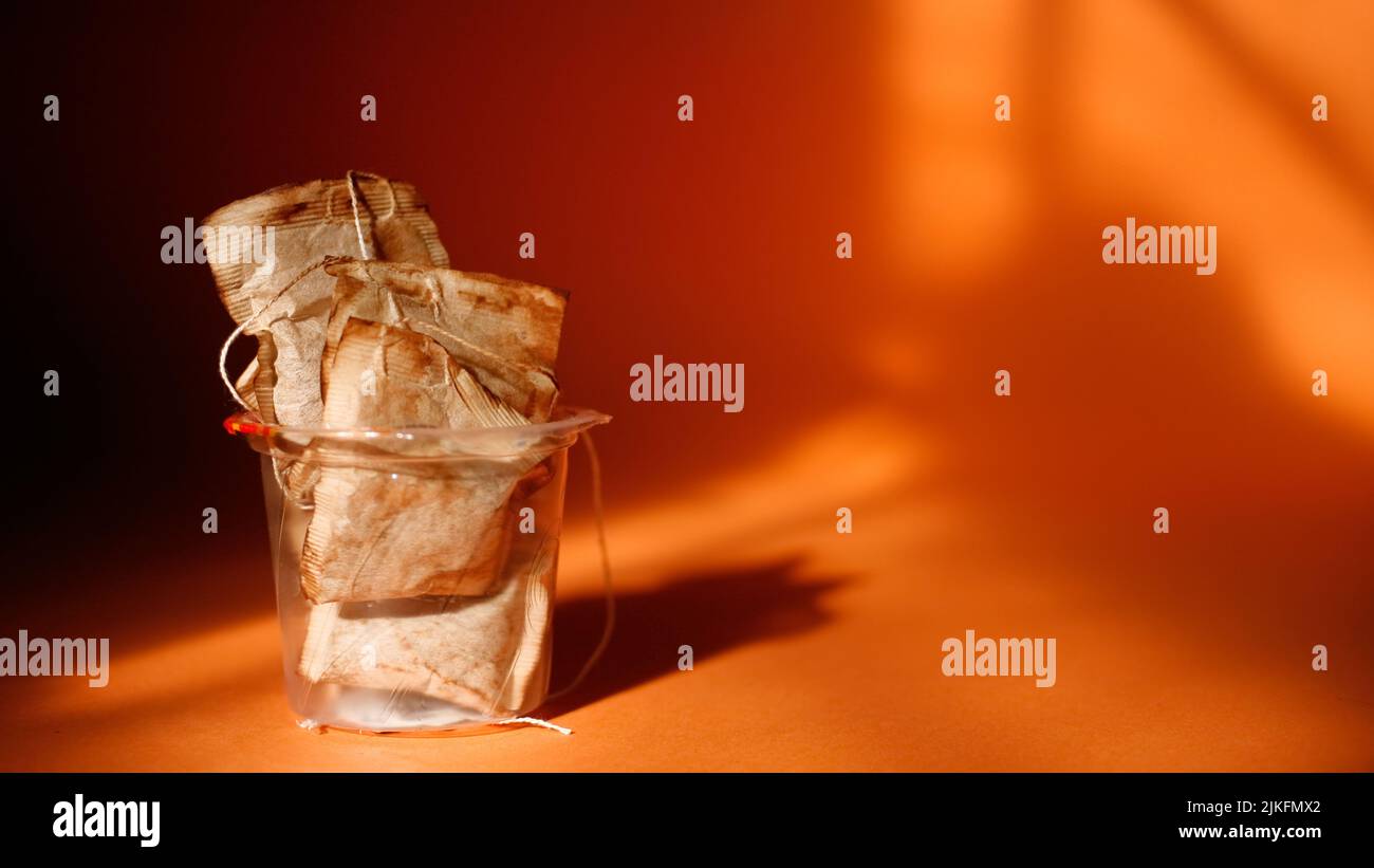 Bicchiere di plastica pieno con bustine di tè usate. Spazio di copia. Primo piano Foto Stock