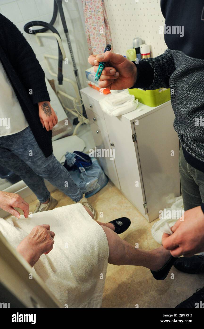 Infermiere privato a casa di un paziente anziano per un'iniezione di insulina con la realizzazione di una glicemia capillare. Foto Stock