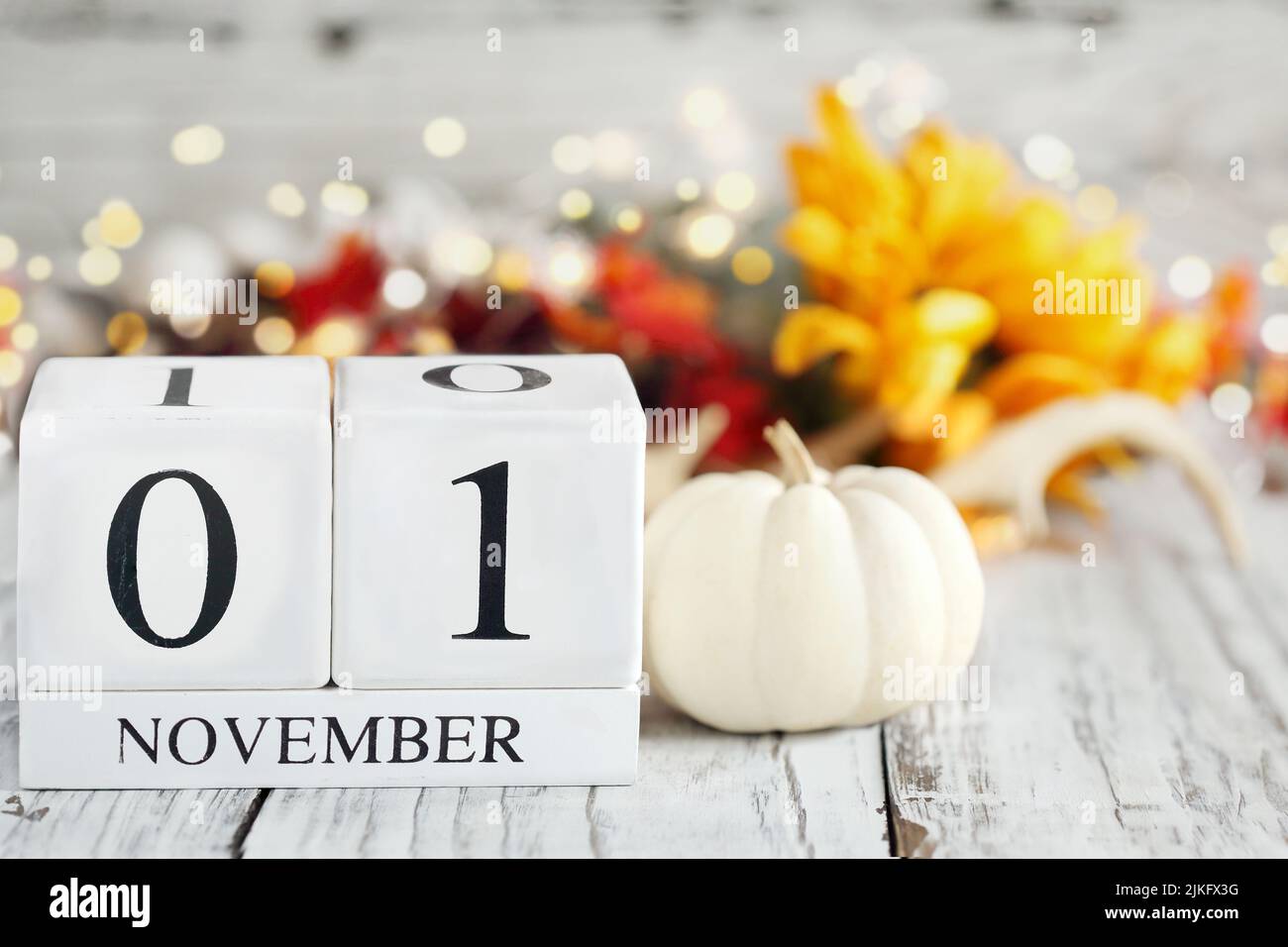 Blocchi di calendario in legno bianco con la data 1st novembre e decorazioni autunnali su un tavolo in legno. Messa a fuoco selettiva con sfondo sfocato. Foto Stock