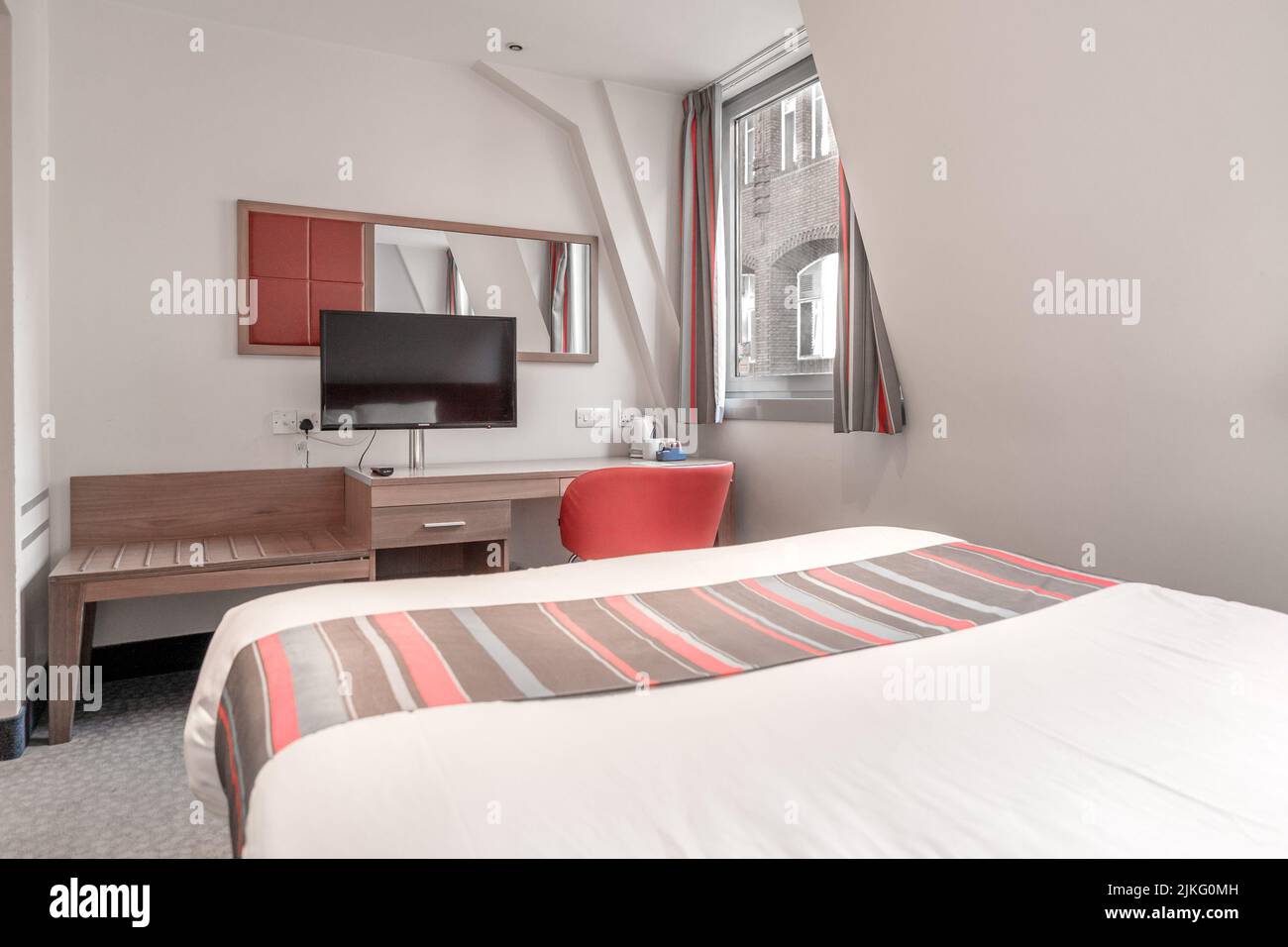 Camera d'hotel con letto doppio e TV. Camera essenziale del Travelodge London Central Aldgate East. Foto Stock