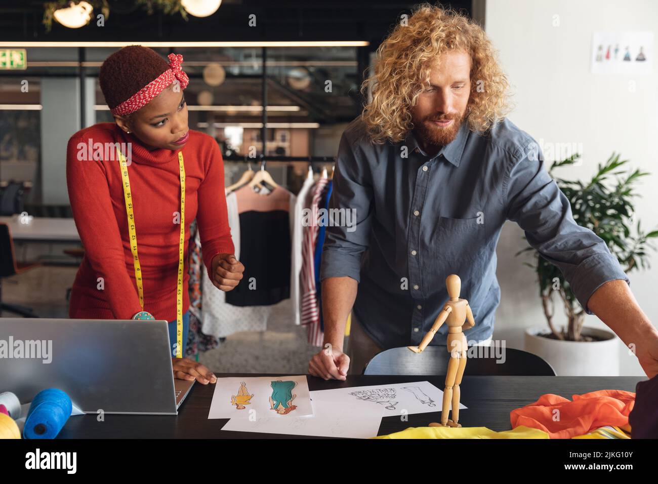 Stilisti di moda maschili e femminili multirazziali che discutono sopra lo schizzo alla scrivania in ufficio Foto Stock