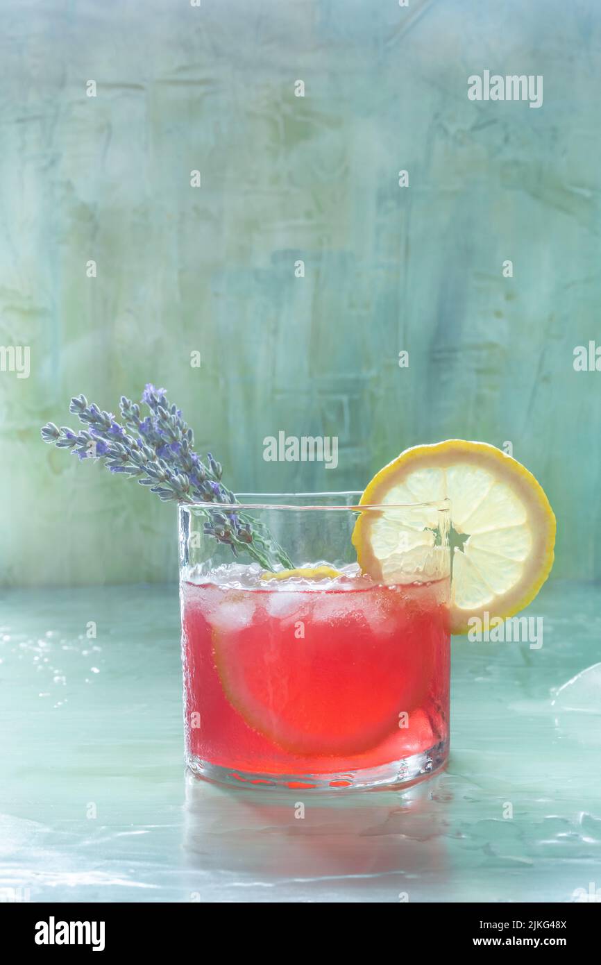 Cocktail estivo o mocktail, una bevanda fredda con limone e lavanda, limonata da festa su sfondo blu con un posto per il testo, una vista laterale Foto Stock
