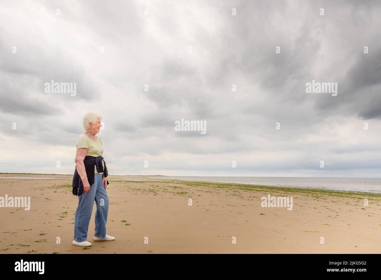 Un'anziana donna caucasica che si posa in terra arida in una giornata nuvolosa Foto Stock