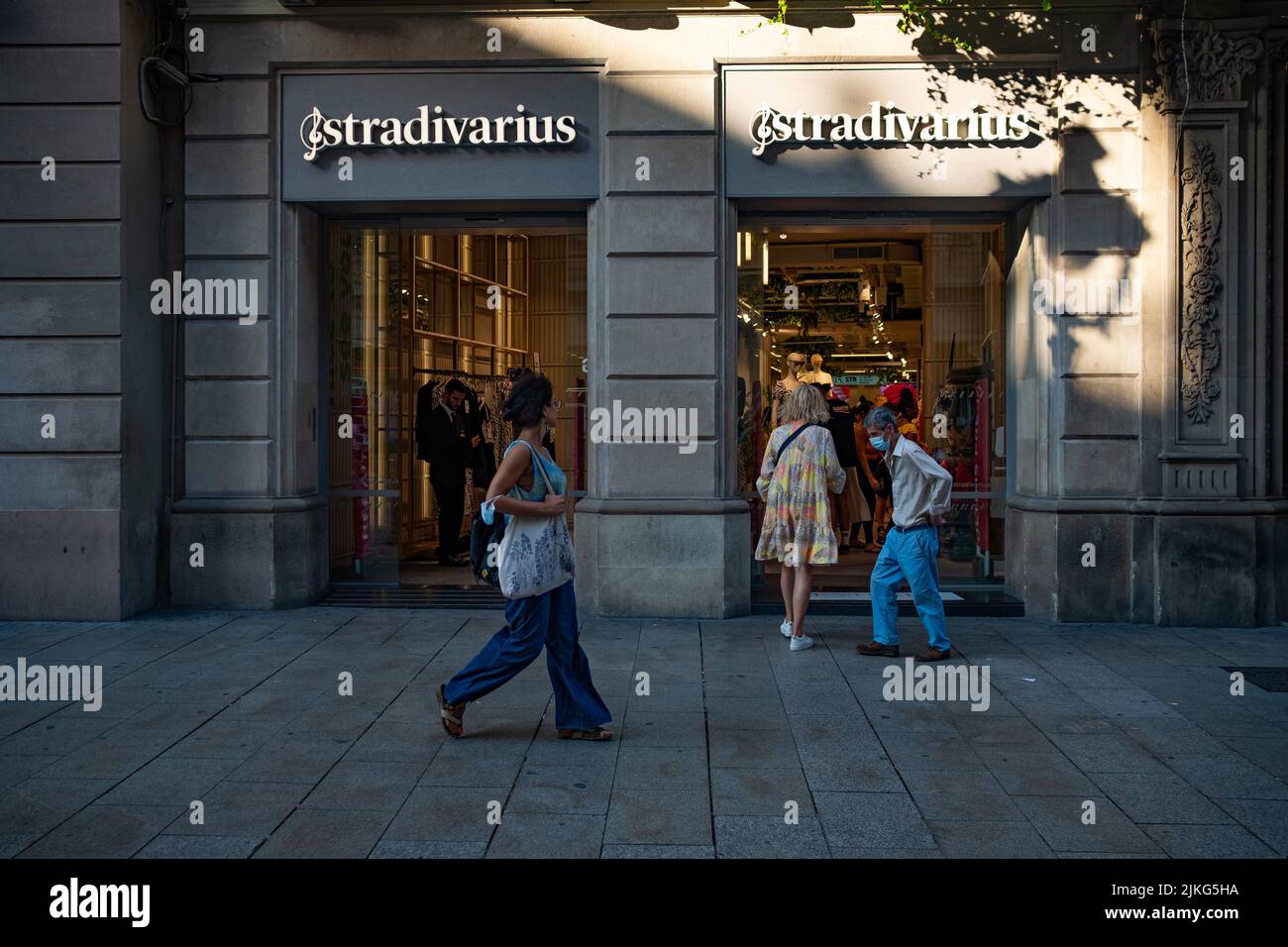 Gli amanti dello shopping e i turisti sono visti passando da un negozio Stradivarius nel centro della città e la strada principale dello shopping Carre de l'Angel a Barcellona, Spagna su 2 Foto Stock