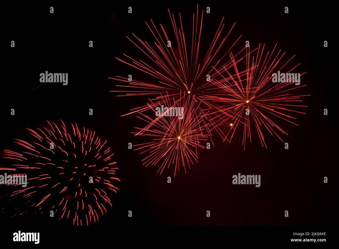 Esplosioni di fuochi d'artificio rosso acceso che riempiono il cielo Foto Stock