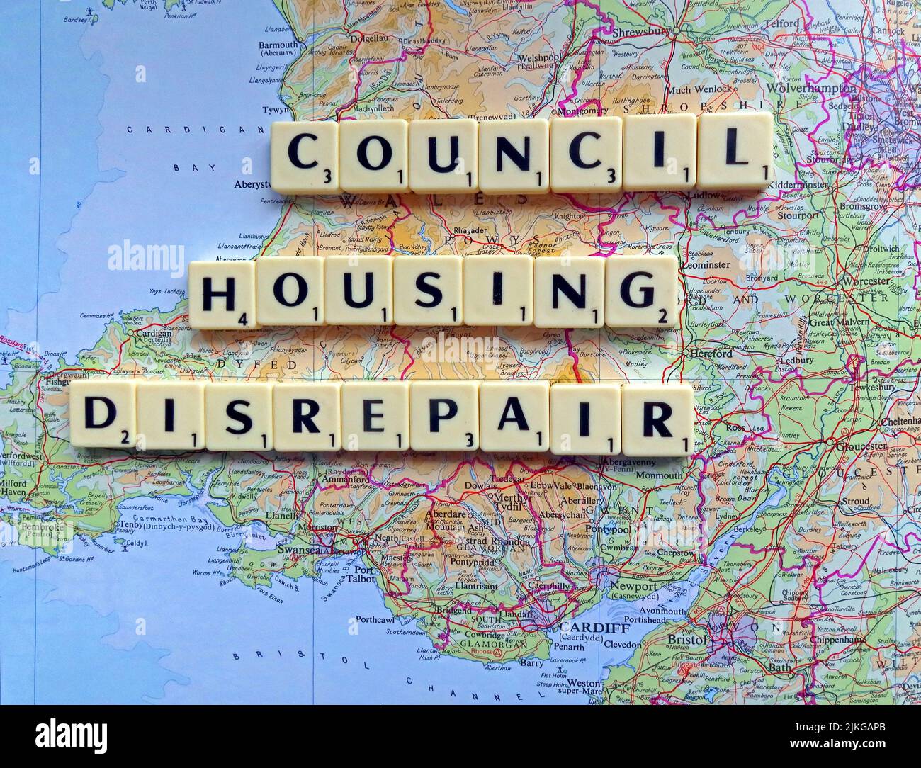 Welsh SocialHousing / Consiglio problemi di riparazione alloggi con riparazioni reattive scritto in lettere Scrabble su una mappa del Galles del Sud Foto Stock