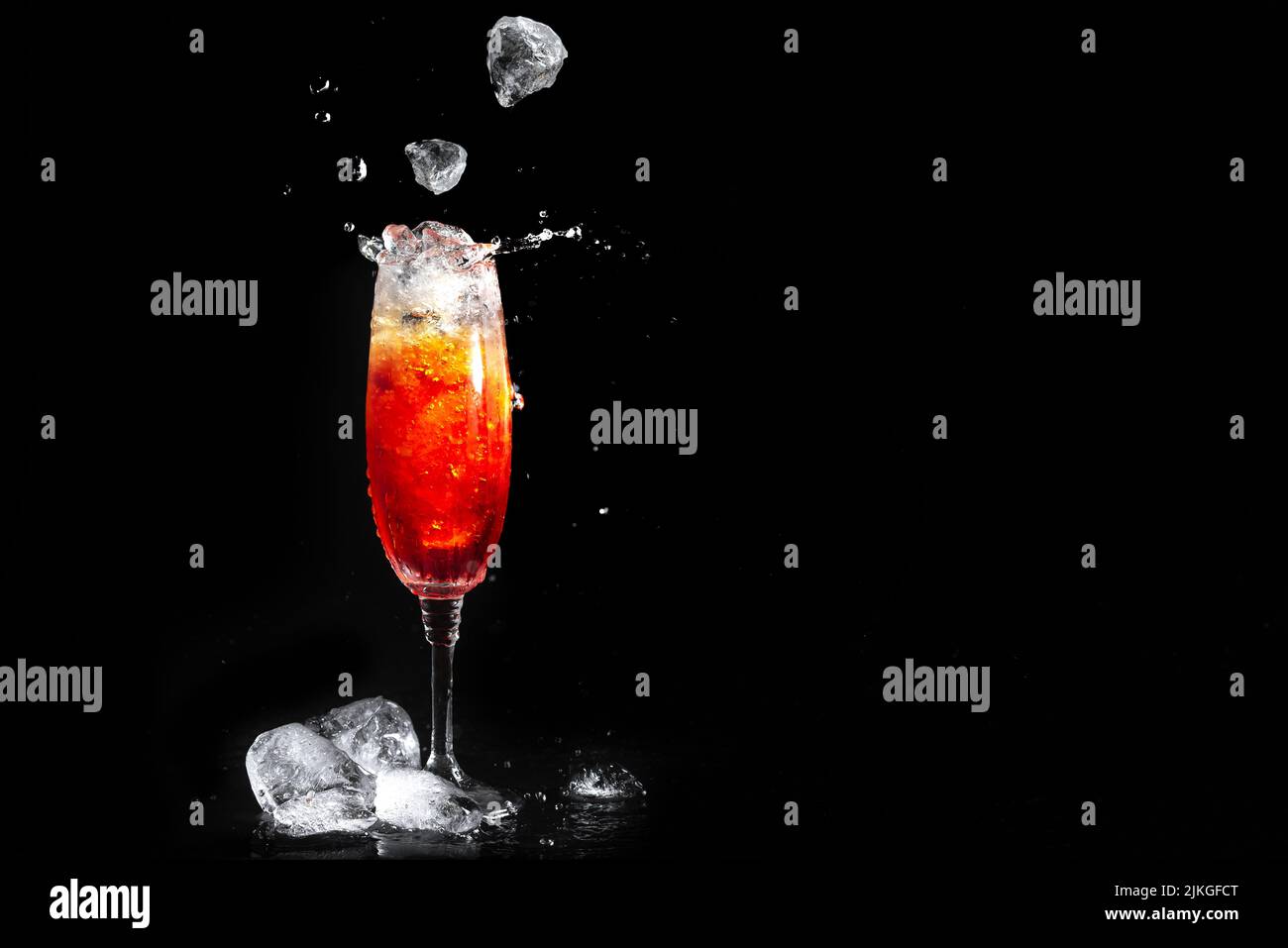 Vetro con cocktail Aperol su sfondo nero. Il ghiaccio cade nel bicchiere con la bevanda alcolica. Un tuffo di cocktail aperol. Drink estivo. Foto Stock