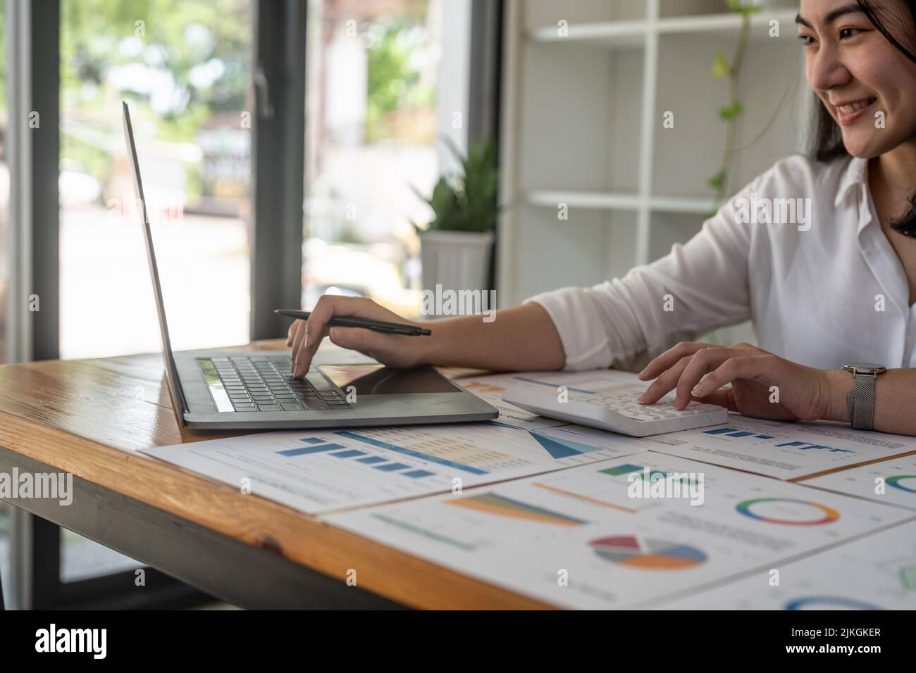 Donna d'affari che lavora investimenti finanziari su calcolatrice e computer portatile. Foto Stock