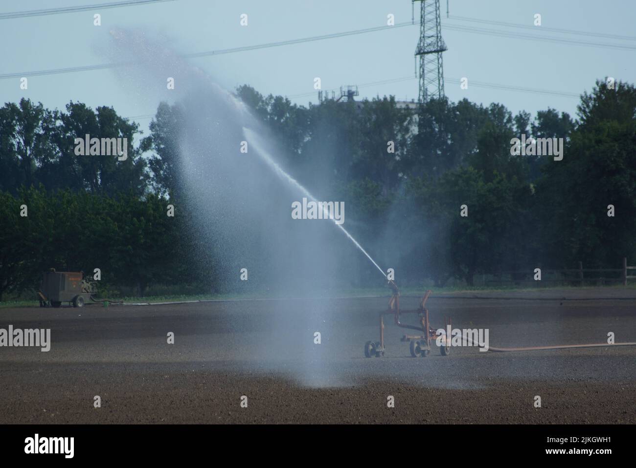 Irrigazione di un campo appena seminato in estate in Assia, Germania. La fontana di spruzzo combatte contro la siccità per salvare il raccolto. Foto Stock