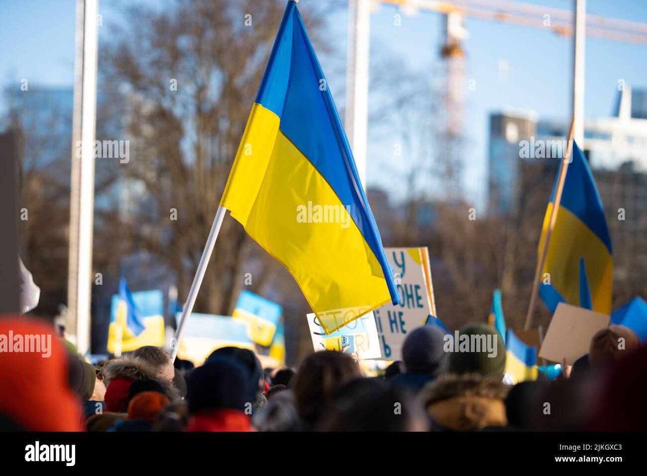 Una grande bandiera Ucraina che sventola in una folla di persone all'aperto durante una protesta Foto Stock