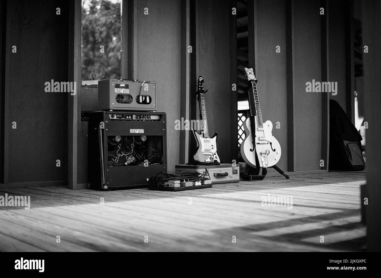 Un tiro in scala di grigi di chitarre e amp gear su un palco Foto Stock