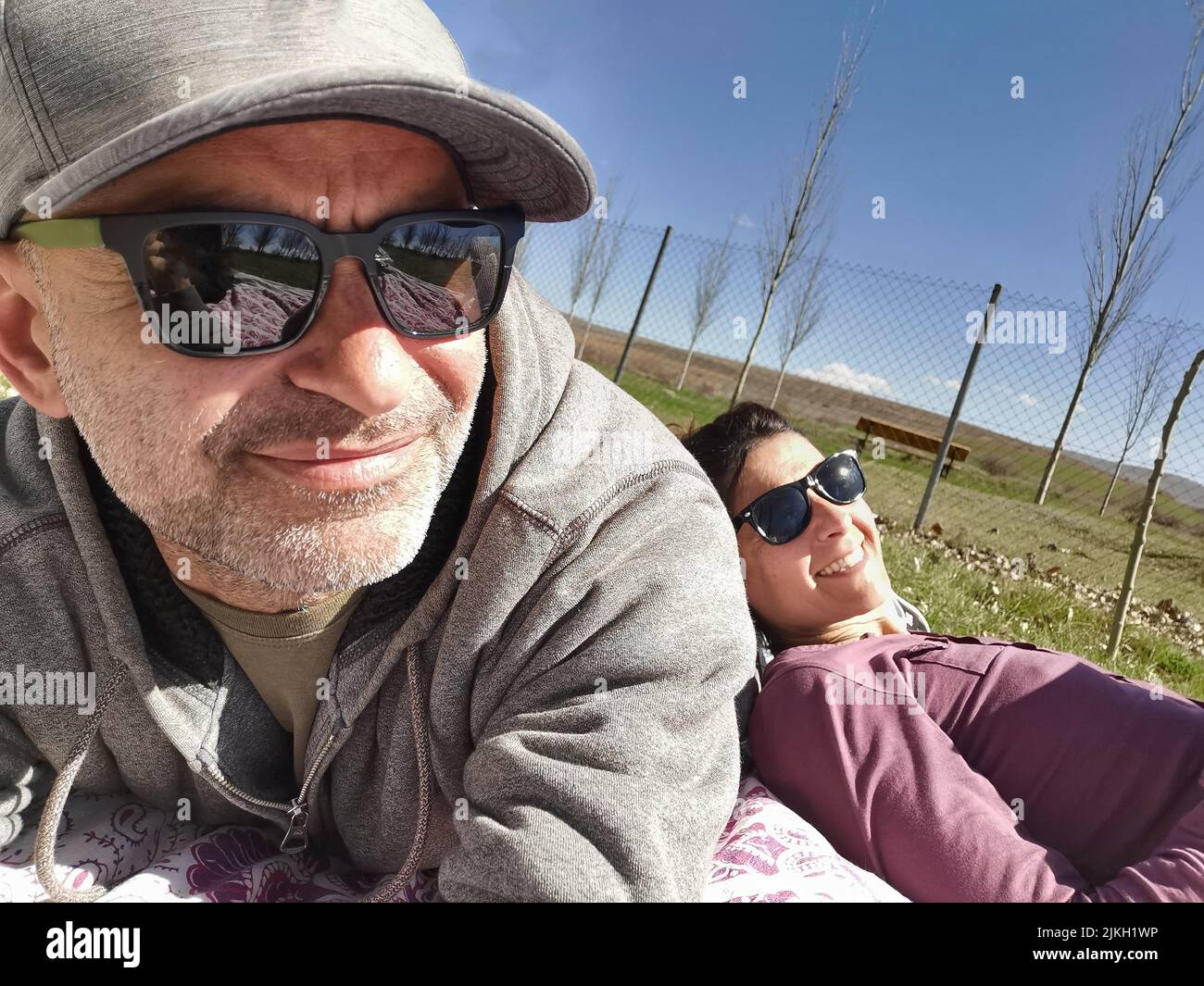 Coppia di mezza età in occhiali da sole appoggiati sull'erba Foto Stock