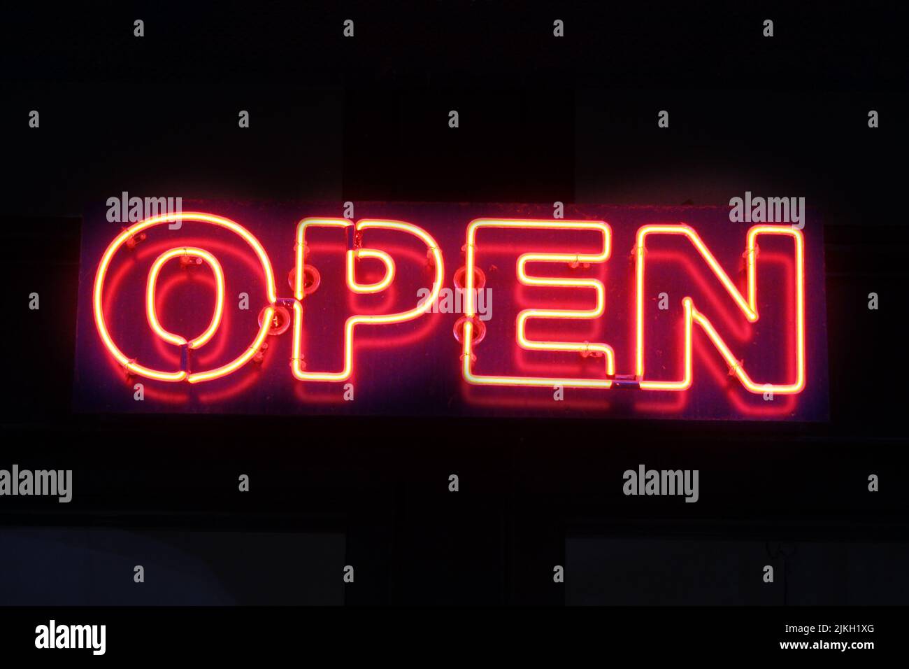 Un segno rosso al neon 'Open' sullo sfondo nero Foto Stock