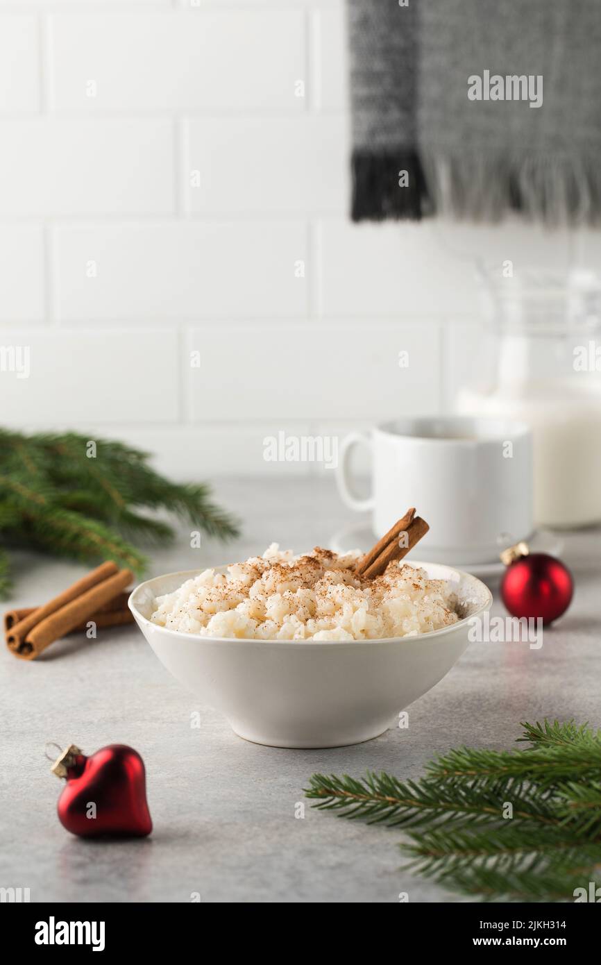 Porridge di riso scandinavo con cannella in una ciotola circondata da palle di Natale. Colazione la vigilia di Natale. Foto Stock